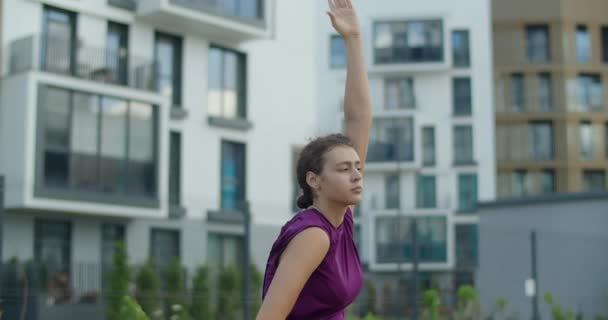 Ung kvinna gör stretching övningar för händer och axlar, uppvärmning träning på gården i en lägenhetsbyggnad, yoga klass i stadsmiljö, fysisk träning och fitness i staden — Stockvideo