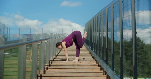 Atletisk kvinna gör stretching övningar på ledstänger av gatan trappor, fitness i stadsmiljö, yoga klass utomhus, fysisk träning i staden, 4k 60p Prores HQ — Stockvideo