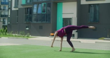 Genç atletik kadın bir apartmanın bahçesinde takla atıyor, şehirde jimnastik yapıyor, açık havada antrenman yapıyor, ağır çekimde fiziksel egzersiz yapıyor, 4k 120p Prores karargahı 10 bit.