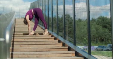 Atletik kadın sokak merdivenlerinin tırabzanlarında esneme egzersizleri yapıyor, şehir ortamında fitness, yoga sınıfı açık havada, şehirde fiziksel egzersiz, 4k 60p Prores HQ