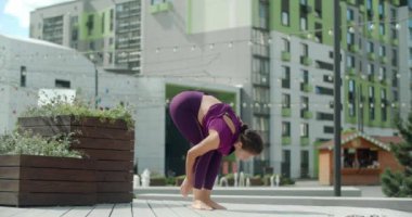 Atletik kadın güneşli bir günde konut bahçesinde esneme egzersizleri yapıyor, şehir ortamında fitness, yoga sınıfı açık havada, şehirde fiziksel egzersiz, 4k 60p Prores HQ
