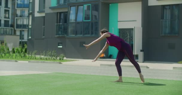 Молодая спортсменка выполняет колесо во дворе жилого дома, гимнастика в городе, тренировки на открытом воздухе, физические упражнения в замедленной съемке, 4k 120p Прорес HQ 10 бит — стоковое видео
