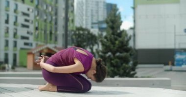 Kadın, yerleşim alanının bahçesindeki bankta esneme ve yoga egzersizleri yapıyor, şehir ortamında spor yapıyor, yoga sınıfında açık havada, şehirde fiziksel antrenman yapıyor, 4k 60p Prores karargahında.