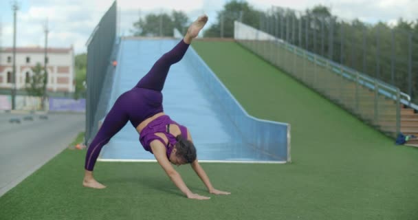 Atletisk kvinde gør strækøvelser, opvarmningstræning i gården i en lejlighedskompleks, fitness i bymiljøet, yoga klasse udendørs, fysisk træning i byen, 4k 60p Prores HQ – Stock-video