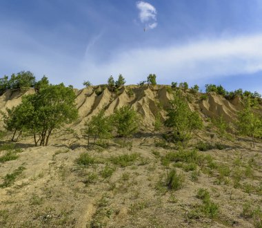 Kireçtaşı çıkarma için ocaklar. Ezilmiş kireçtaşı küçük yığınları oluşan ve yağmurlar tarafından yıkanmış bir höyük.  