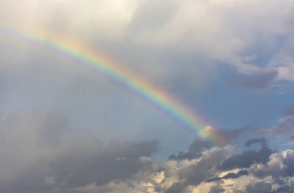 Rainbow in the spring cloudy sky after a thunderstorm and rain.