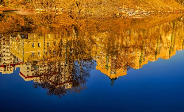 Reflection of houses in the water of the river. Abstract pattern created by the ripples.