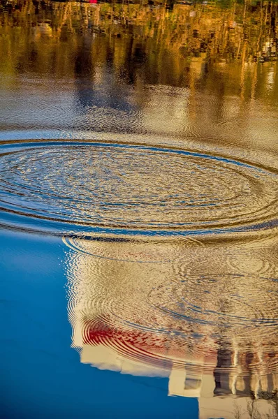 Reflection of houses in the water of the river. Abstract pattern created by the ripples.