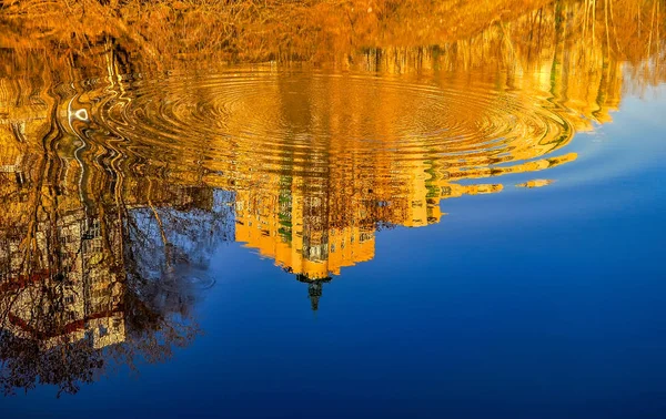 Reflection of houses in the water of the river. Abstract pattern created by the ripples.