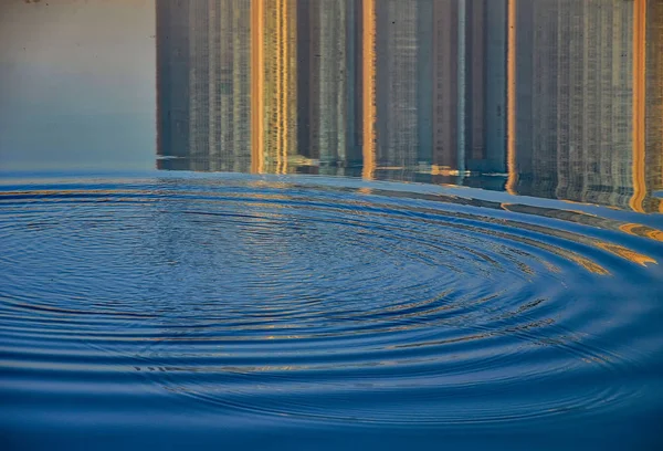 Reflection of houses in the water of the river. Abstract pattern created by the ripples.