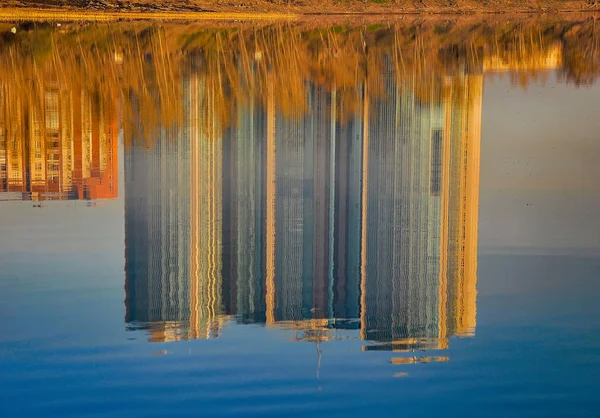 Reflection of houses in the water of the river. Abstract pattern created by the ripples.