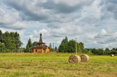 Arka planda saman balyaları ve ahşap kilise ile Yaz kırsal peyzaj