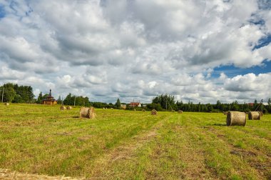 Arka planda saman balyaları ve ahşap kilise ile Yaz kırsal peyzaj