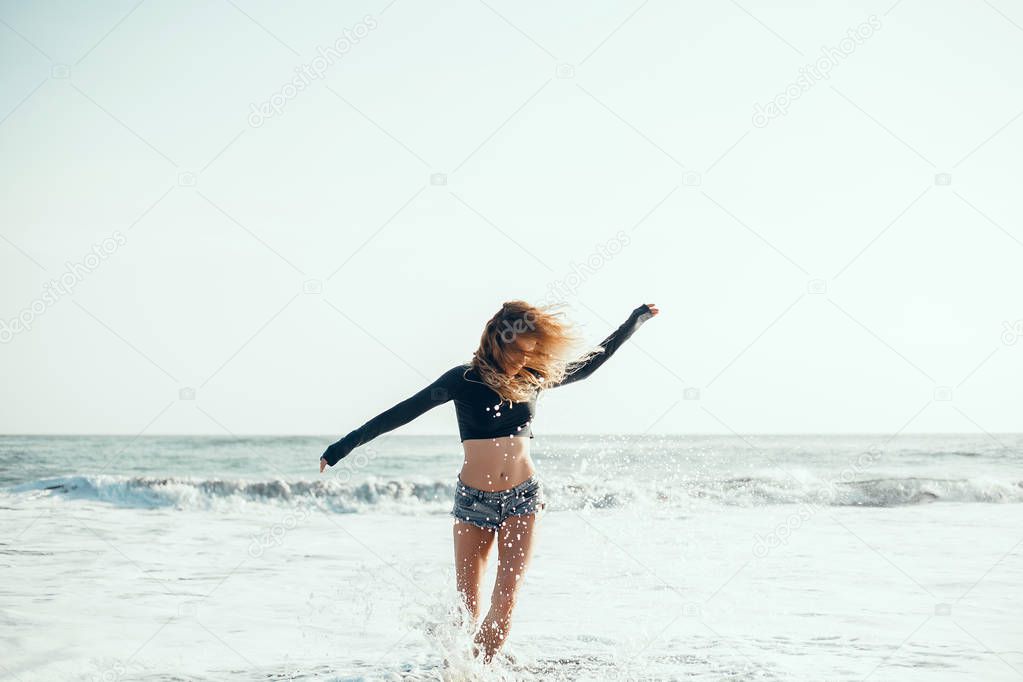 young beautiful girl posing on the beach, ocean, waves, bright sun and tanned skin