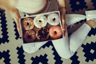 Güzellik model kız tatlılar ve renkli çörekler alarak. Pembe arka plan üzerinde tatlılar ile Komik neşeli Vogue tarzı kadın. Diyet, diyet konsepti. Abur cubur, Zayıflama, kilo kaybı