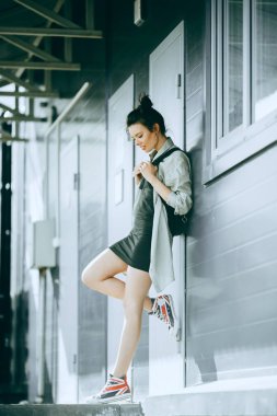 Siyah elbiseli genç kız dışarıda duruyor ve şehirde gün batımını seyrediyor, güneş bir kızın üzerinde ışıl ışıl, şık kıyafetler, hipster tarzı, çanta, güneş, sokak fotoğrafı, özgürlük, New York