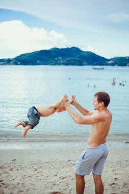 Baba oğlunu parka geri götürüyor. Mutlu bir babanın portresi. Oğlunu sırtında taşıyor ve yukarı bakıyor. Babasıyla dışarıda oynayan sevimli bir çocuk. Küçük bebek babasıyla poz veriyor. Bali