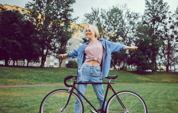 Beauty woman posing in the street with bicycle, outdoor hipster portrait,