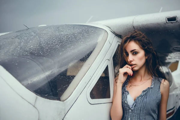 Young pretty woman posing near aircraft, woman looking at sky with clouds from the airplane window. sunset with a height of 10 000 km. woman face close up