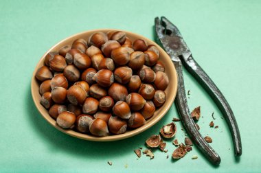 Fındık ve yeşil zemin üzerine pense ile kase