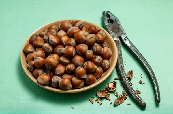 Fındık ve yeşil zemin üzerine pense ile kase