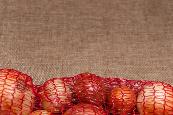 Cebollas Envases Malla Roja Sobre Tela — Foto de Stock