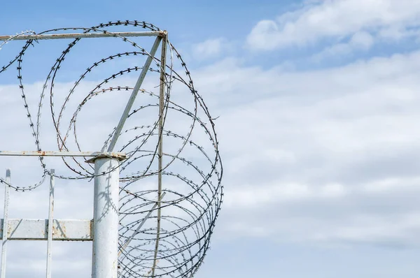 mavi gökyüzünde dikenli tel ile demir çit