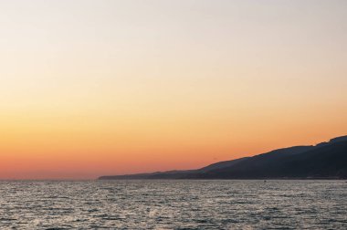 bir yaz gününde gün batımında deniz manzarası ve dağlar