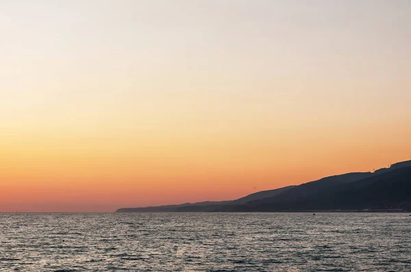 bir yaz gününde gün batımında deniz manzarası ve dağlar