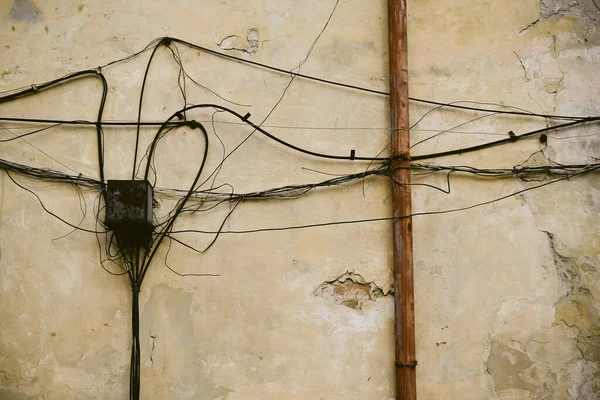 Eski tuğla duvardaki elektrik kabloları. Tuğla duvardan sarkan elektrik kabloları