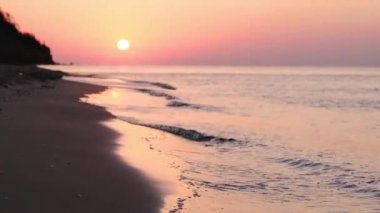Denizin üzerindeki güneş. Sahilde inanılmaz kırmızı bir gün doğumu. Turuncu renkler gündoğumu ve dalgalar. Dramatik deniz batımı. Yavaş Hareket 4K