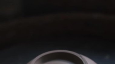 Bükülmüş Çömlek Tekerleği 'nde el yapımı kilden bir kupa. Çömlekçiler yakın plan çalışırlar. Potter kil rulo