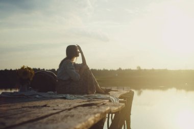 Ahşap bir iskelede poz veren şık elbiseli çekici bir genç kız. Film ve Tahıl Efektli Fotoğraf