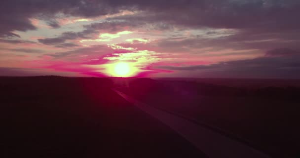 Vista Areial de uma longa estrada reta e um céu colorido ao pôr-do-sol. 4K — Vídeo de Stock