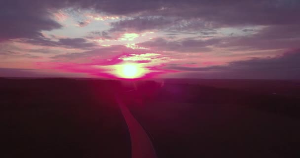 Vista Areial de uma longa estrada reta e um céu colorido ao pôr-do-sol. 4K — Vídeo de Stock