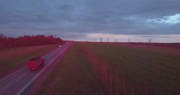 Flygfoto över landskapet med en tur på lastbilarna och ett par bilar vid solnedgången och moln. 4k — Stockvideo