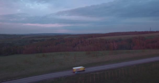 Vista aérea da paisagem com um passeio sobre os caminhões da estrada e alguns carros ao pôr do sol e nuvens. 4K — Vídeo de Stock