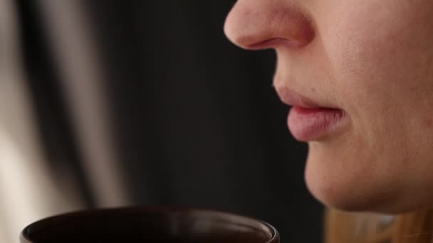 Beautiful woman drinks coffee or tea looking out the window. slow motion — Stock Video