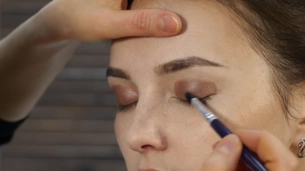 Artista de maquillaje profesional hace maquillaje de ojos en una cara de cliente. belleza moda industria — Vídeos de Stock