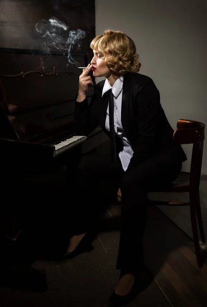 Красивая женщина в деловом костюме играет на пианино — стоковое фото