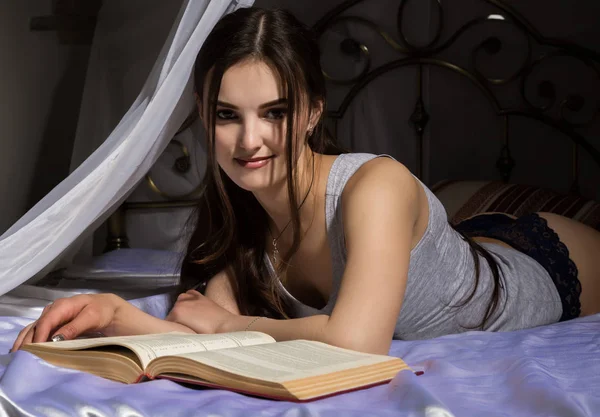 Studentka v posteli a číst knihy, kterým dívka sní o životě — Stock fotografie