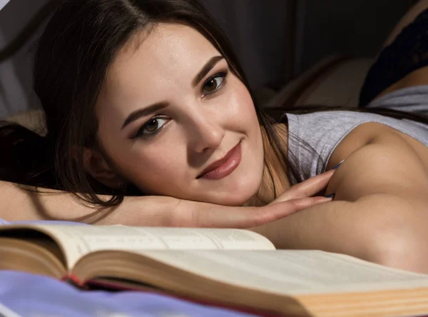 Estudiante mujer acostada en la cama y leer libro, chica soñando con la vida — Foto de Stock
