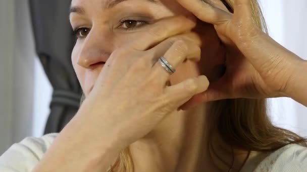 Mujer rubia haciendo auto-masaje, masaje facial anti-envejecimiento en la oficina. acondicionamiento físico de la cara diaria y construcción facial . — Vídeo de stock