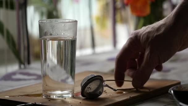 Glass of hot water with a tea infuser. preparing tea. slow motion — Stock Video