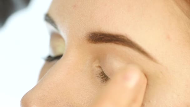 Primer plano maquillaje artista mano, la aplicación de sombra de ojos a las mujeres ojo usando los dedos . — Vídeo de stock