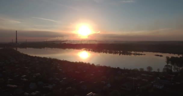 Vista aérea. puesta de sol sobre el lago con la pequeña ciudad en una orilla. Planta industrial en un horizonte. 4K — Vídeo de stock