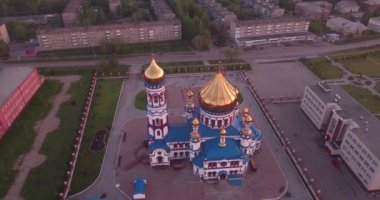 Küçük kasabada yeni kilise çevresinde uçan hava. Hıristiyan Tapınağı ve şafakta altın kilise kubbe. 4k