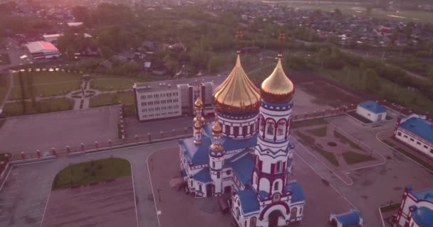 Vuelo aéreo alrededor de la nueva iglesia en la pequeña ciudad. Templo cristiano y cúpula dorada de la iglesia al amanecer. 4K — Vídeos de Stock