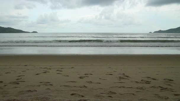 Sjøkappe med bølger på sandstranden. overskyet himmel og tropiske strand – stockvideo