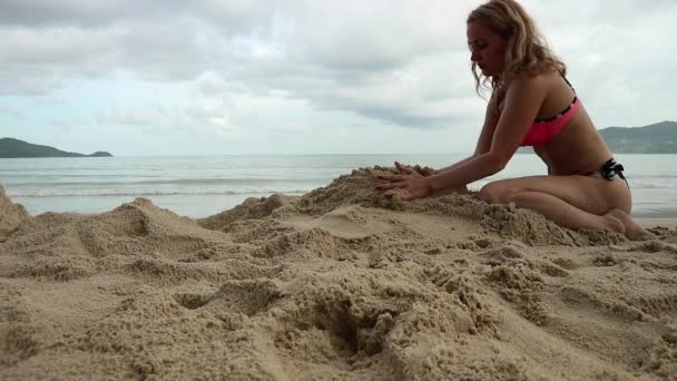 Красивая стройная женщина играет с песком на экзотическом пляже — стоковое видео